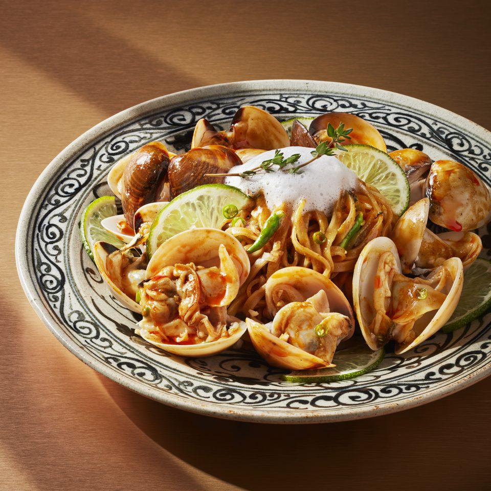 Lanna vongole khao soi: clams and egg noodles in curry with lime, on a patterned plate